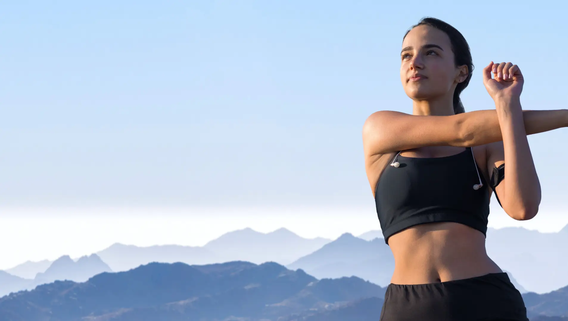 Eine Sportlerin dehnt sich in der Natur.