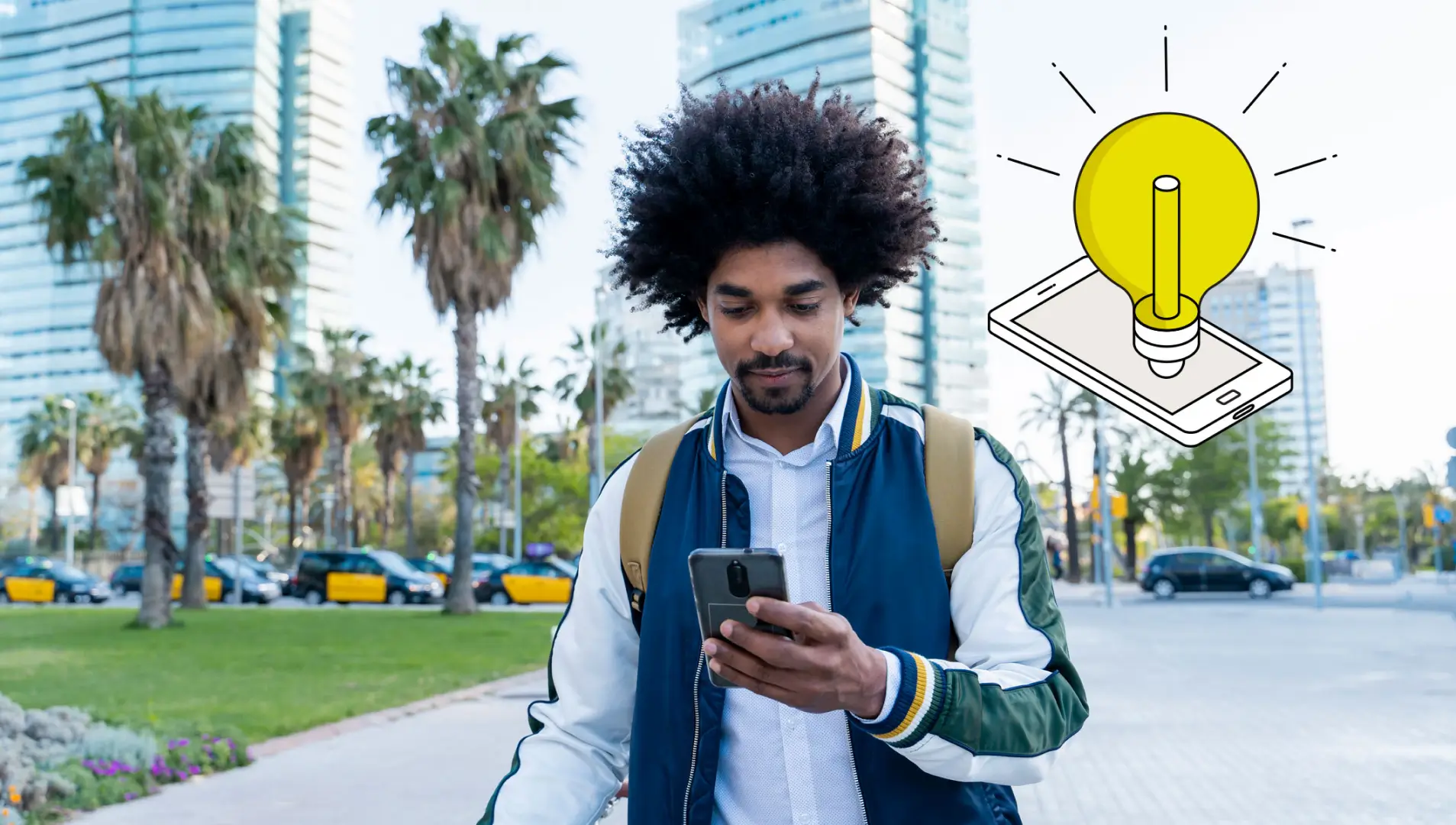 Ein junger Mann schaut auf sein Smartphone während er durch eine Großstadt geht.