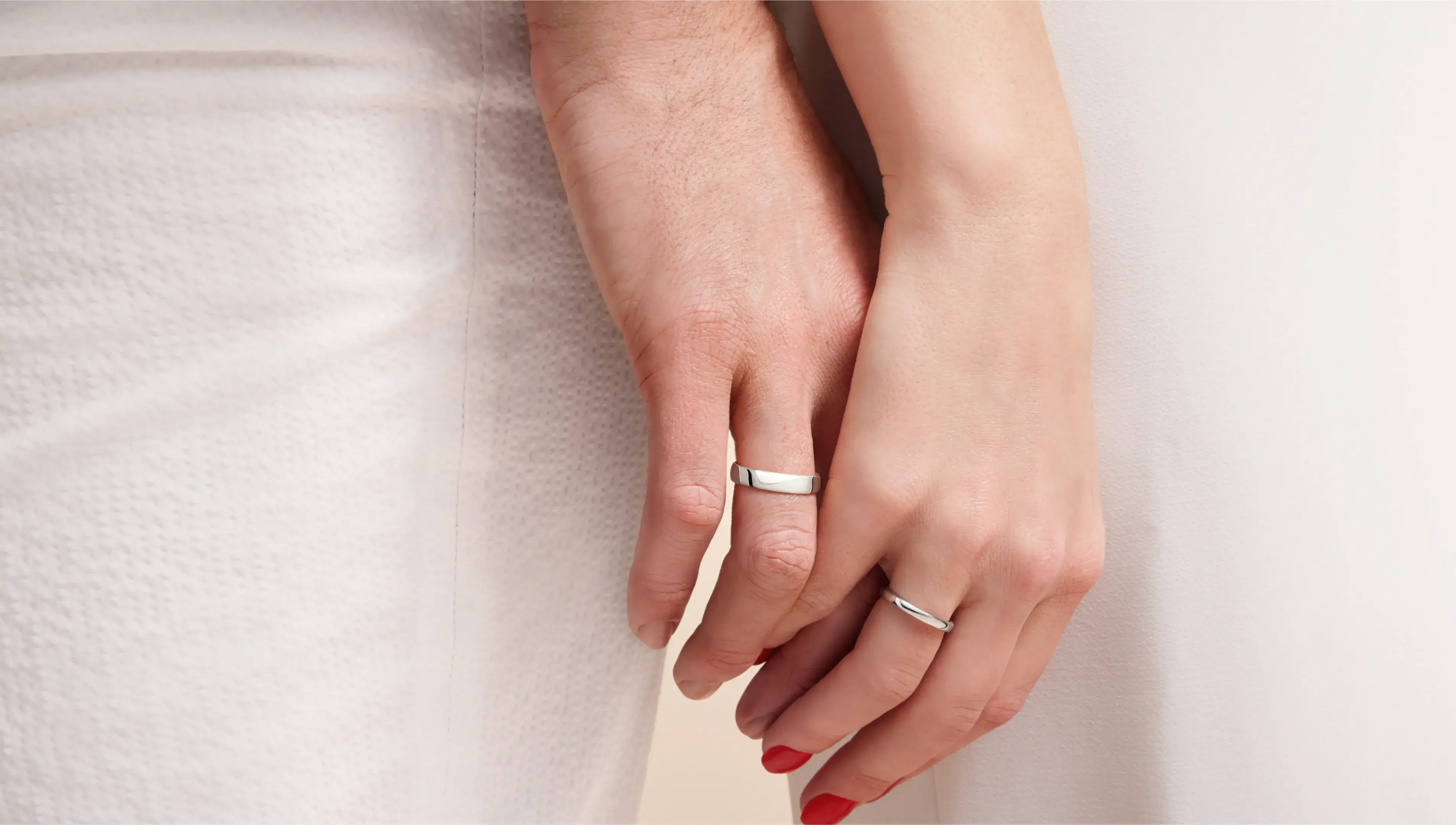 Zwei Hände in Nahaufnahme mit silbernen Eheringen am Finger.