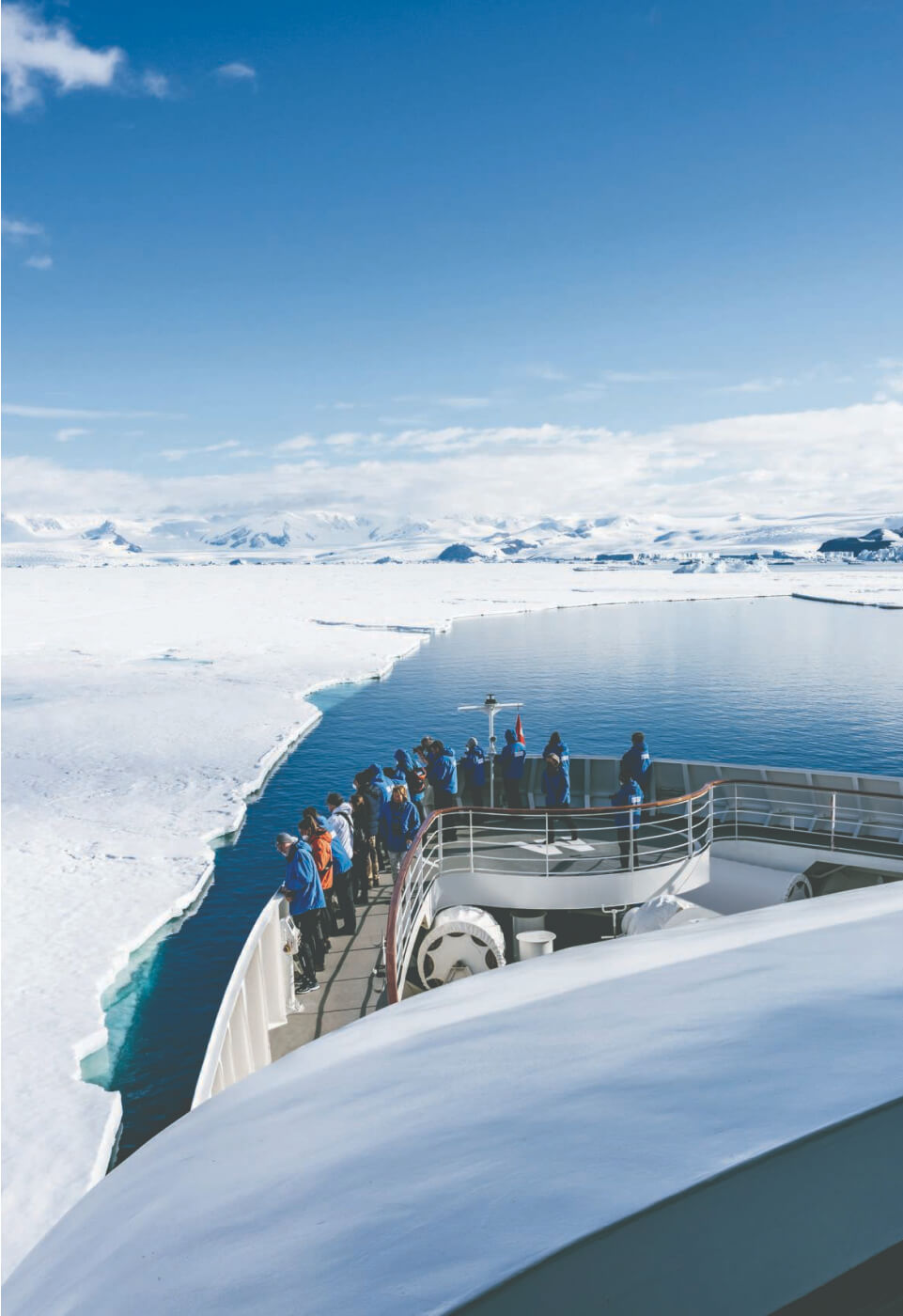 Der vordere Bereich eines Schiffes in der Arktis mit Menschen die ins Meer schauen.