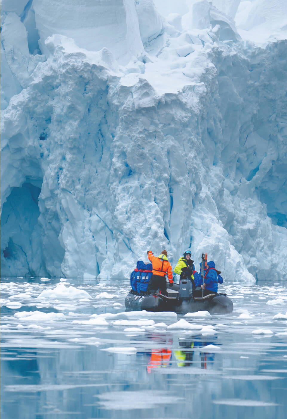 Ein paar Menschen auf einem Ruderboot die im Eismeer schwimmen.
