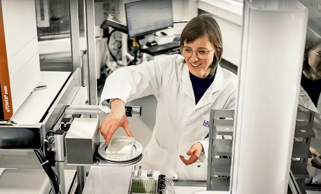 Dr. Luzia Gyr lächelnd an einem technischen Gerät in einem modernen Labor.