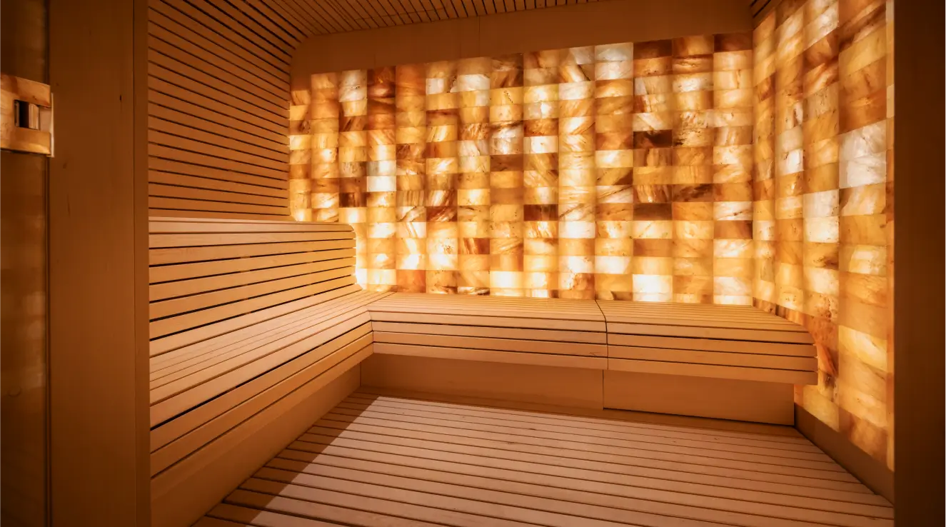 Mareel Spa - Eine moderne Sauna mit hölzernen Bänken und einer hinterleuchteten Salzwand bietet eine warme und einladende Atmosphäre.