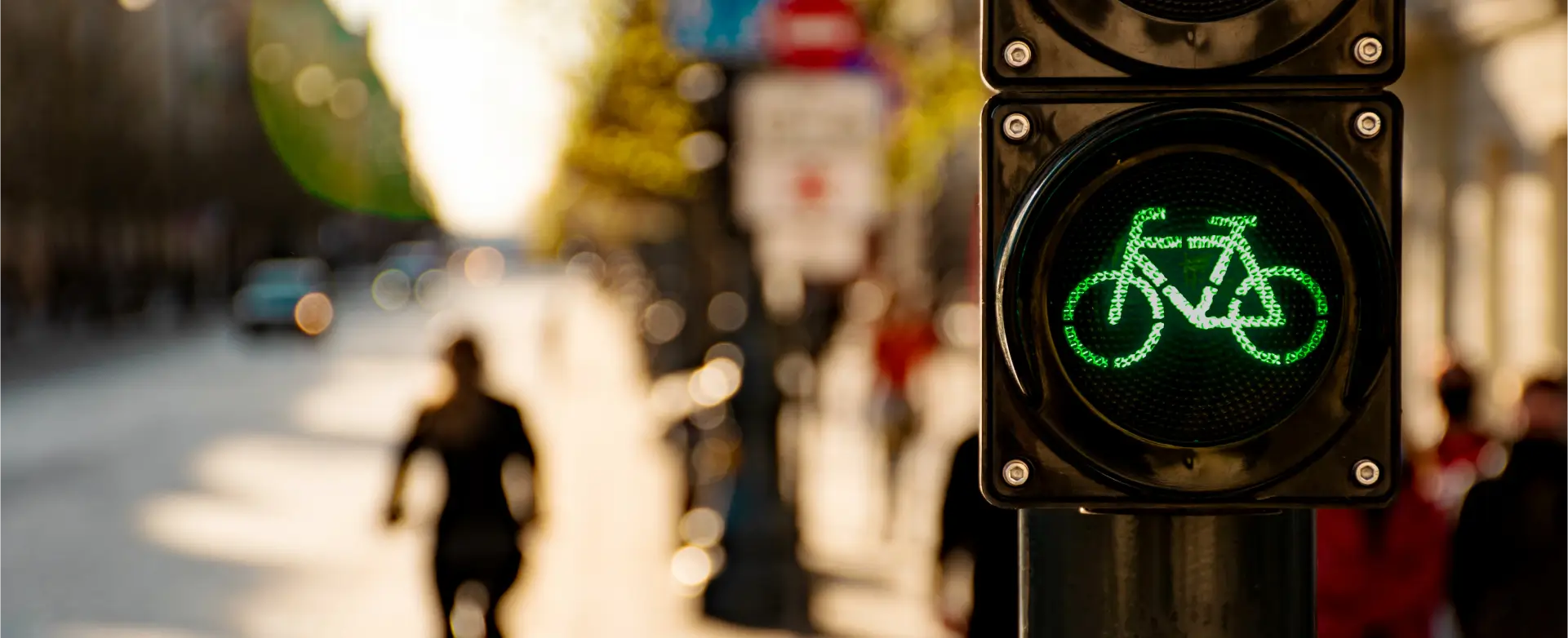 Das Bild zeigt eine grüne Ampel mit einem Fahrrad-Symbol, die Radfahrern das Überqueren einer Straße in einer städtischen Umgebung erlaubt.