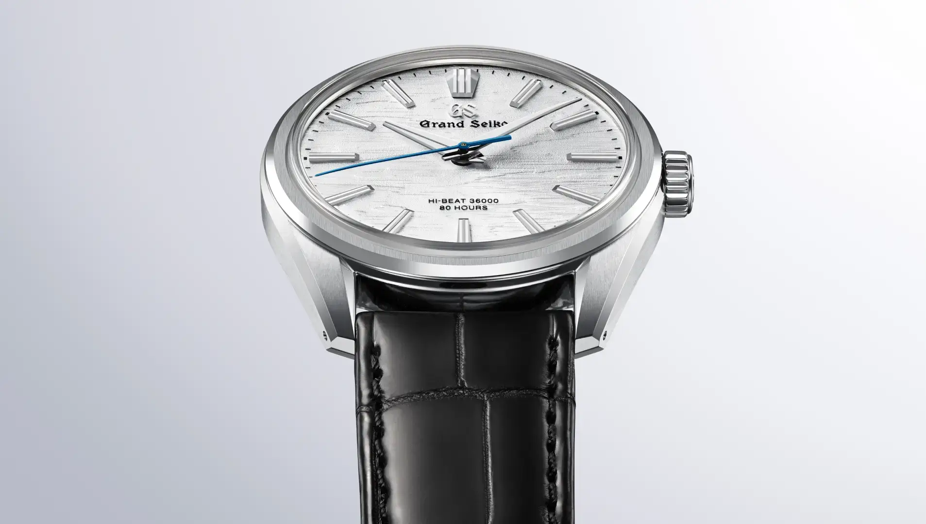 Diese Grand Seiko Uhr zeichnet sich durch ein silbernes Zifferblatt mit feiner Textur, elegante Stundenmarkierungen, einen blauen Sekundenzeiger und ein schwarzes Lederarmband aus.