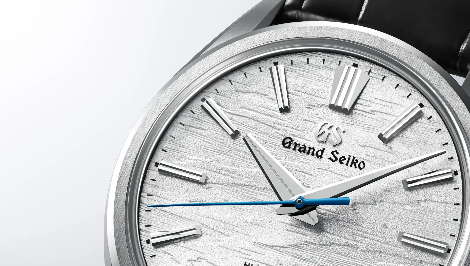 Diese Grand Seiko Uhr besticht durch ein silbernes, texturiertes Zifferblatt, markante Stundenmarkierungen und Zeiger sowie einen auffälligen blauen Sekundenzeiger.