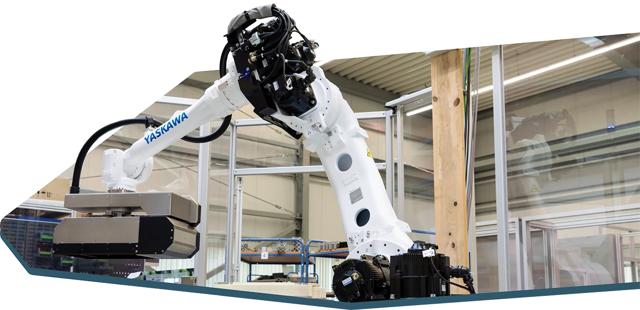 Ein industrieller Roboterarm der Marke Yaskawa in einer Fabrikumgebung. Der Arm ist weiß und mit verschiedenen mechanischen Komponenten ausgestattet. Im Hintergrund sind Metallrahmen und Fabrikbeleuchtung zu sehen.