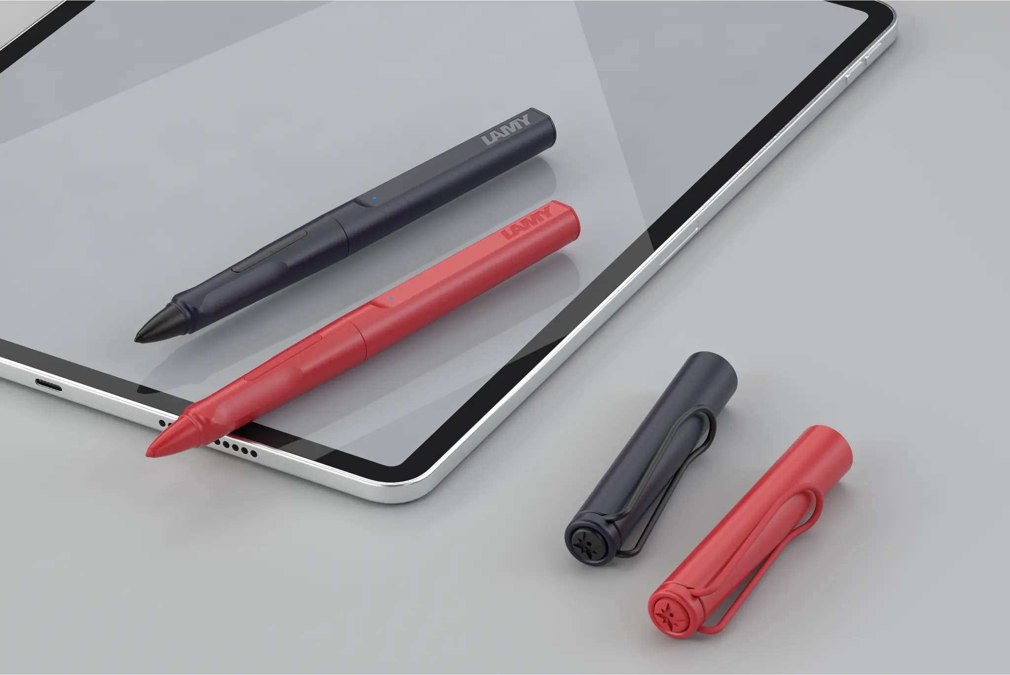 Ein Tablet mit zwei digitalen Stiften liegt auf einem grauen Hintergrund. Ein Stift ist schwarz, der andere rot. Beide Stifte haben ihre Kappen daneben liegen.