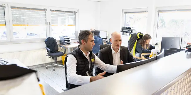 Zwei Personen arbeiten gemeinsam an Computern in einem modernen Büro.