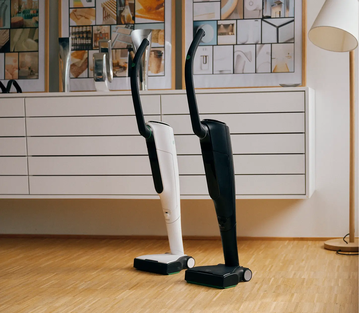 Eine Person sitzt auf einem grünen Sessel und spricht, während im Hintergrund ein Staubsauger zu sehen ist.