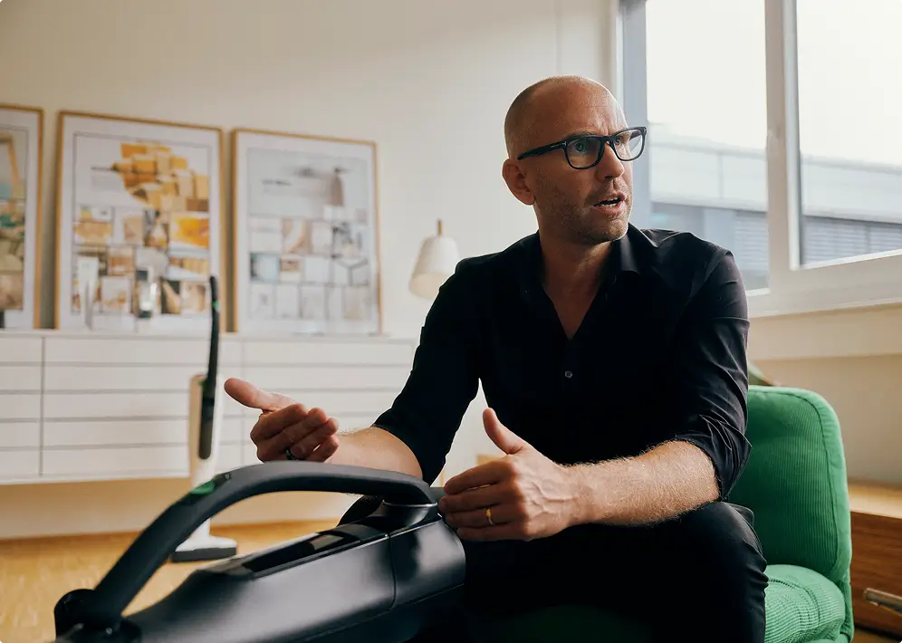 Eine Person sitzt in einem modern eingerichteten Raum und gestikuliert während eines Gesprächs.