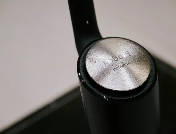 Display eines schwarzen Haushaltsgeräts mit leuchtender Anzeige und einem Smiley.