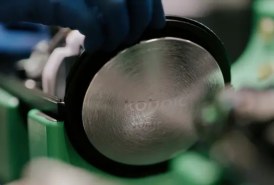 Detailaufnahme eines silbernen Kobold-Motors mit Gravur, umgeben von grünen Bauteilen