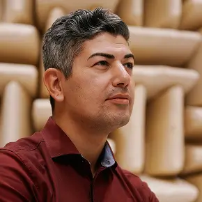 Mann mit graumeliertem Haar und bordeauxfarbenem Hemd vor schallabsorbierenden Wandpaneelen