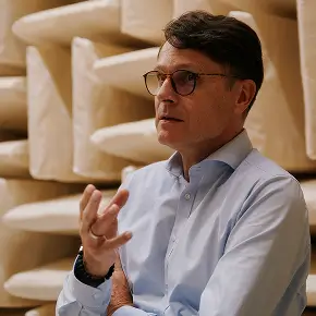 Mann mit blauem Hemd gestikuliert vor schallabsorbierenden Wandpaneelen