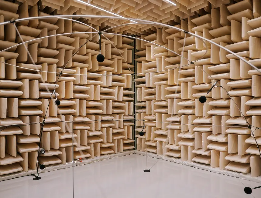 Schalldämmraum mit beigen Schaumstoffkeilen an Wänden und Decke sowie Mikrofonen auf Stativen
