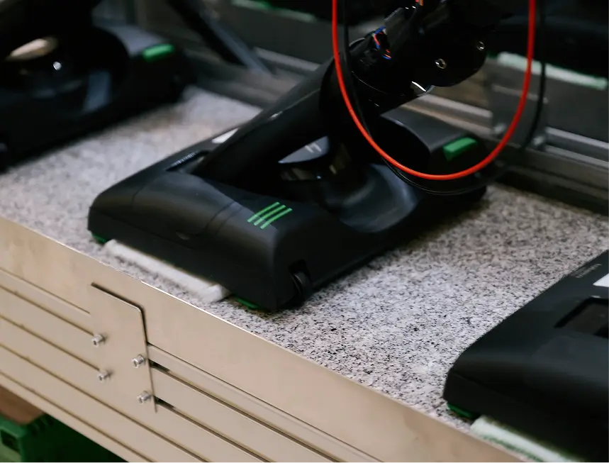 Mehrere schwarze Staubsauger mit Kabeln auf grauer Arbeitsplatte in Prüfstation