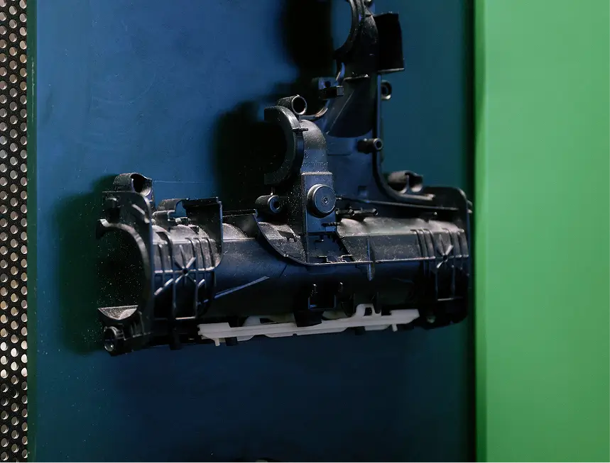 Schwarzes Kunststoffgehäuse eines Staubsaugerroboters auf blauer Arbeitsmatte