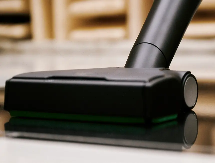 Schwarze Staubsaugerdüse auf glänzendem Boden vor schallabsorbierenden Wandpaneelen