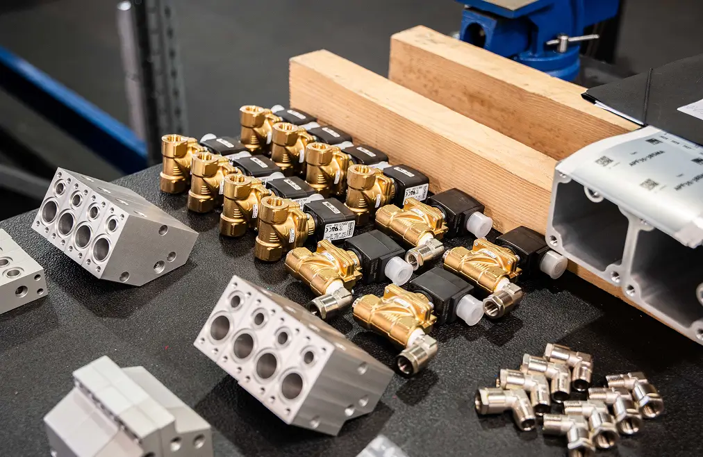 Kleine Metall- und Messingteile, wie Ventile und Anschlüsse, auf einer Werkbank.
