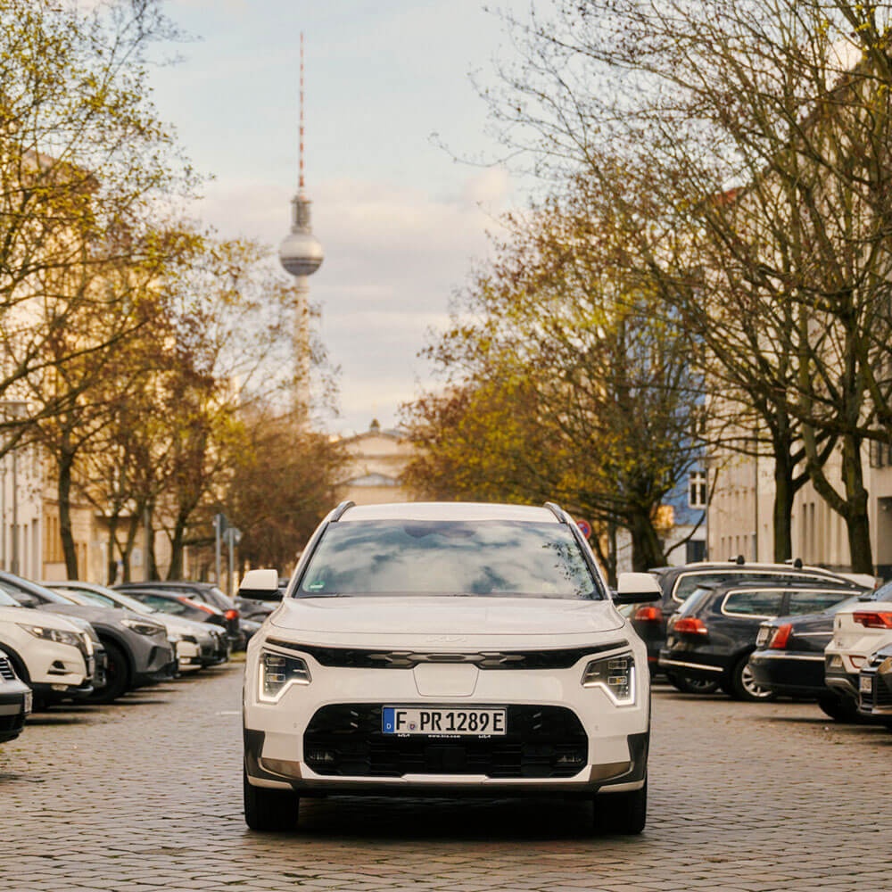 Der Kia Niro EV auf einer Straße in Berlin. Im Hintergrund ist der Fernsehturm zu sehen.